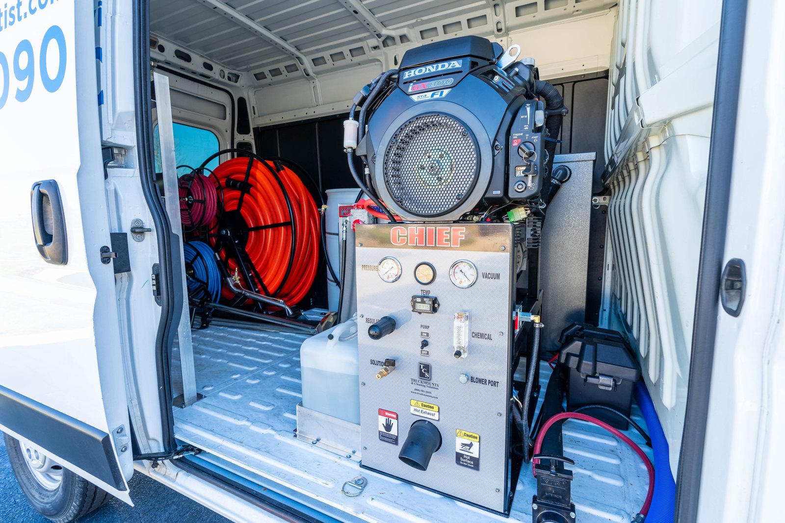 The Chief truckmount installed at the cargo van side door, with its engine, control panel, and hose reels visible.