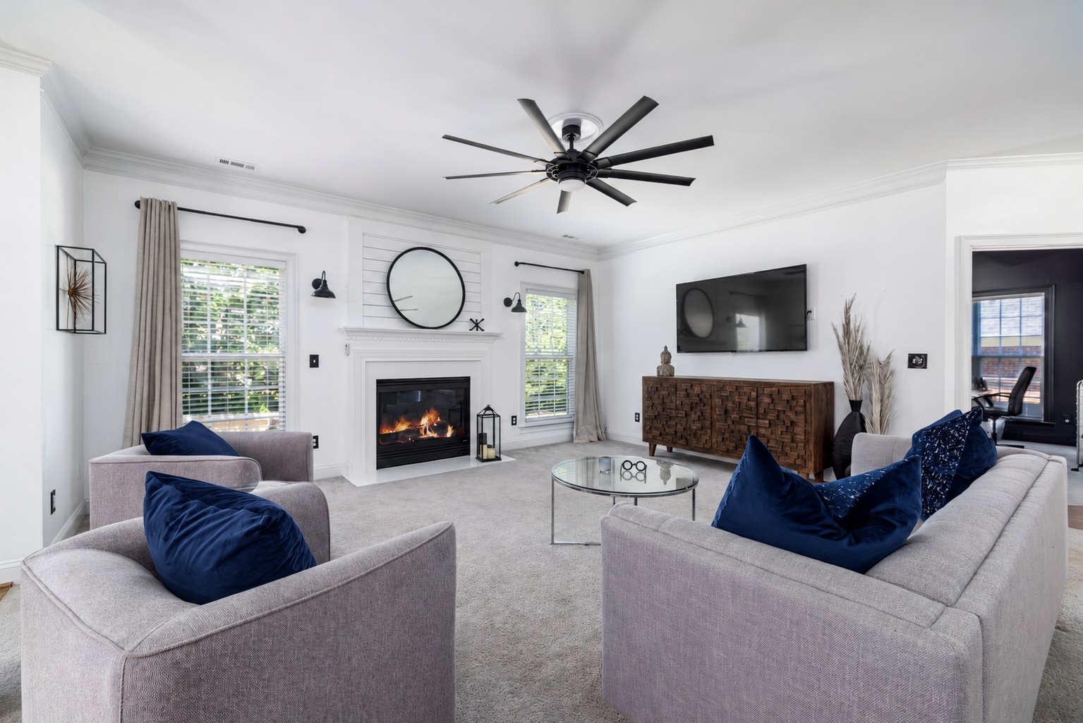 A modern living room with blue pillows and a light carpet.