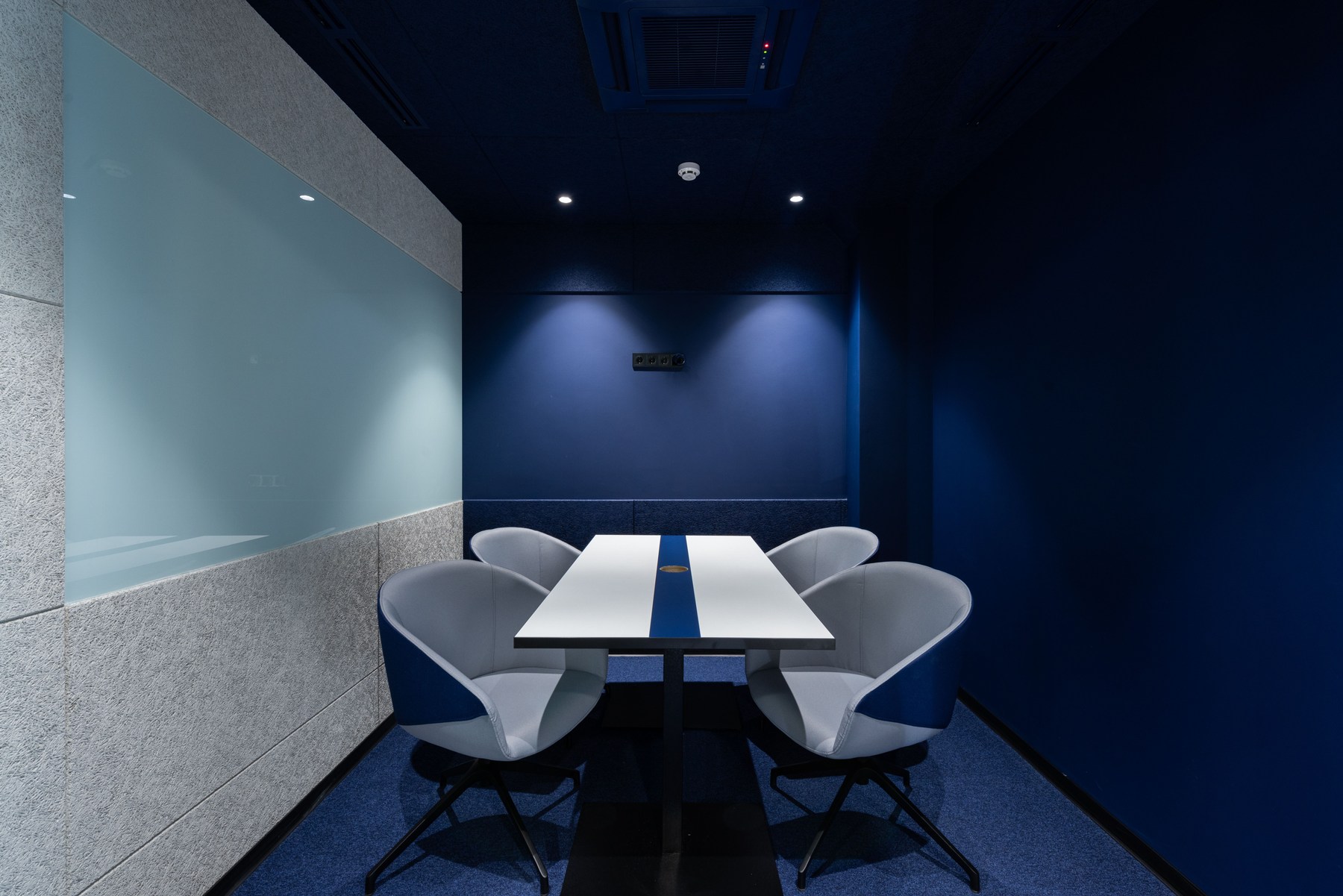 A compact commercial conference room with navy walls and carpeted flooring.