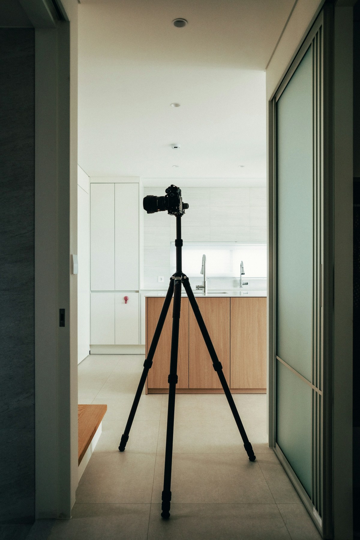 A camera on a tripod positioned to photograph a prepared kitchen interior.